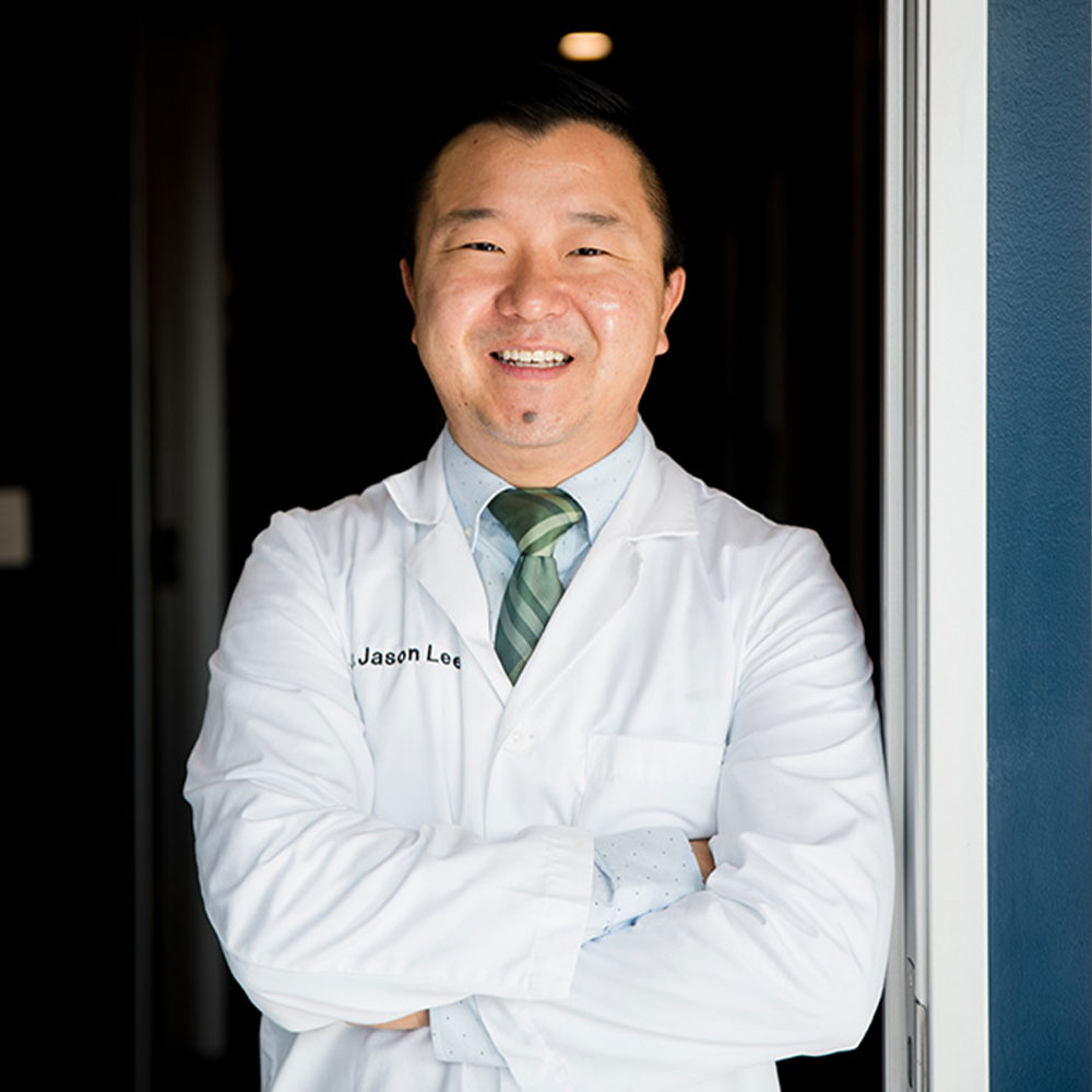 The image features a woman standing in front of a dental office, wearing a white coat and holding her arms crossed.