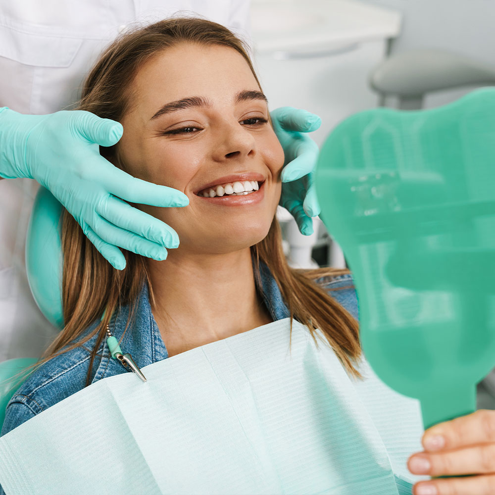 A dental professional is assisting a patient with a digital display of the patient s mouth, highlighting dental work in progress.